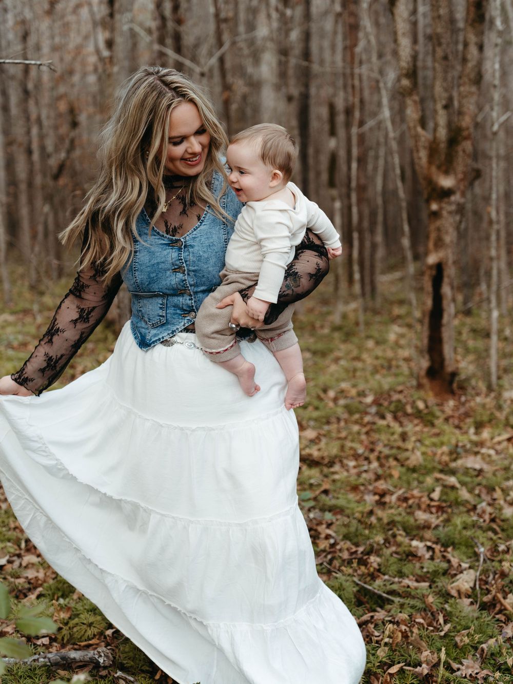 Michaela Lee holding her baby in a wooded field